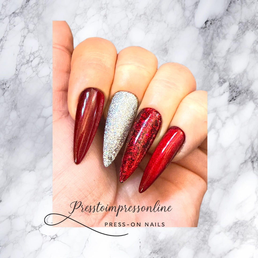 “Hand wearing long red and silver stiletto press-on nails from Presstoimpressonline displayed on a marble background.”