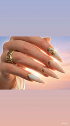 Luxury handmade champagne shimmer press-on nails with pearlescent ivory accents, gold glitter French tips, and gold embellishments from the Antigua At Sunset Collection.