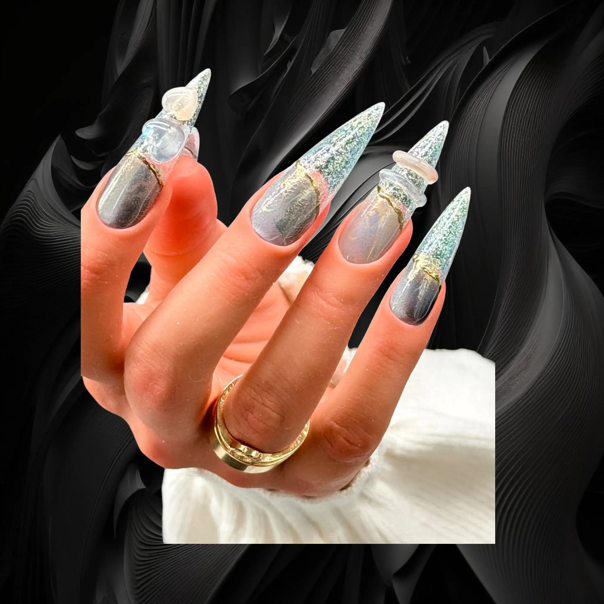 Luxury stiletto press-on nails with blue cat eye effect, fine glitter, chrome lace detailing, and 3D heart and ring charms
