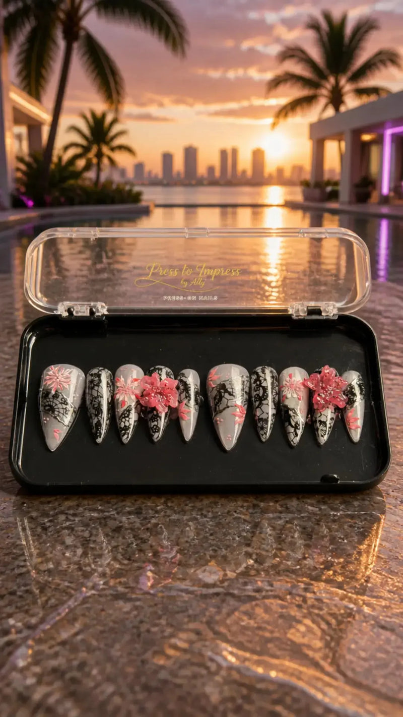 Handmade luxury press-on nails featuring silver chrome, black lace nail art, hand-painted pink cherry blossoms, 3D floral accents, glossy finish, and long stiletto shape.