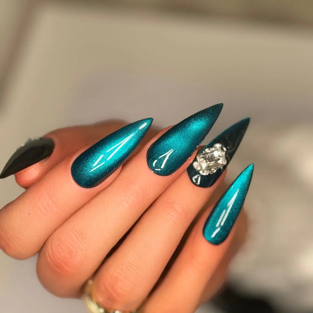 Deep emerald green stiletto press-on nails with metallic chrome finish and crystal accent nail.