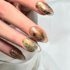 Close-up of Gilded Folklore press-on nail with intricate black vintage-style illustration, gold accents and metallic details