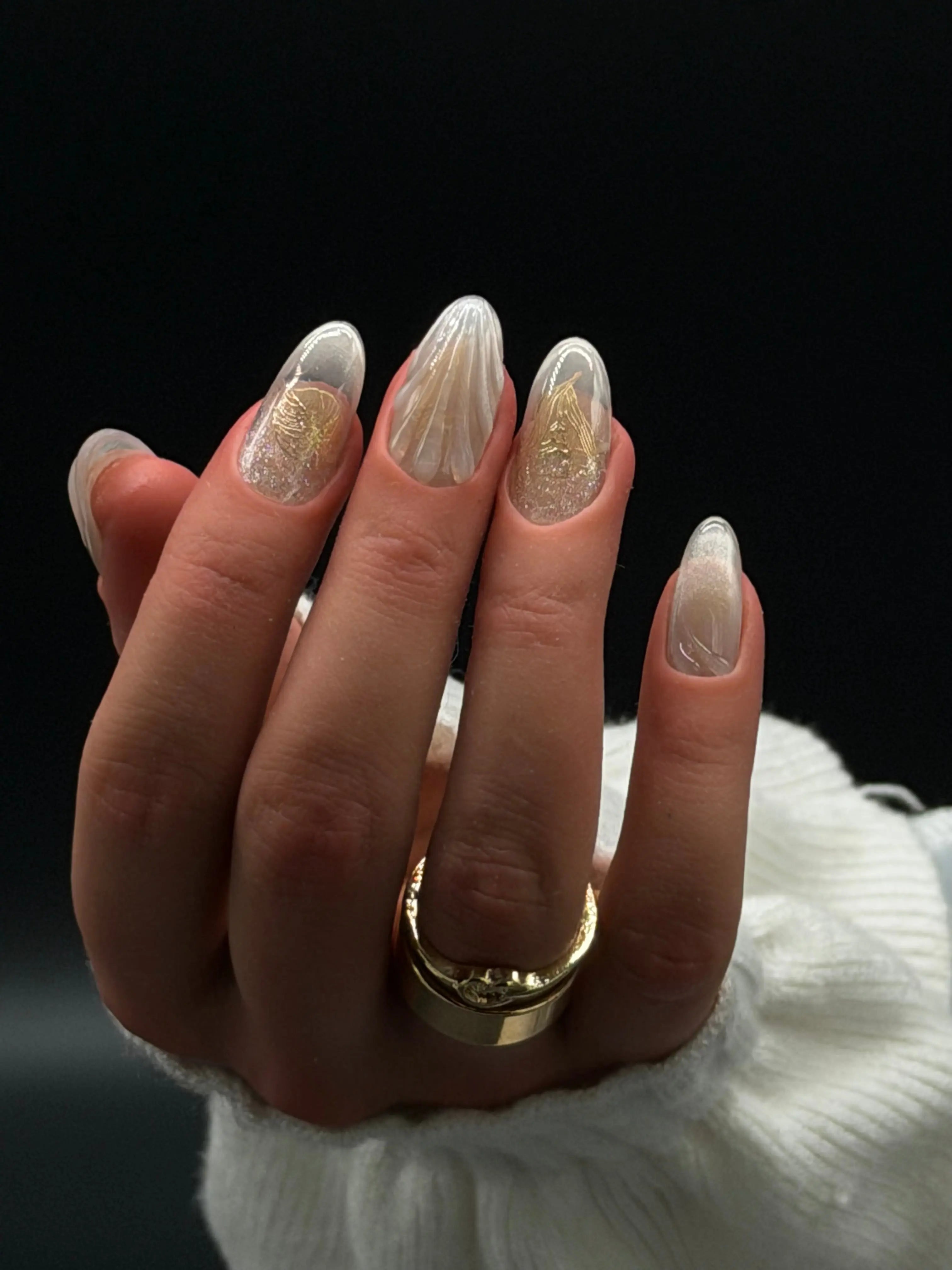 Luxury round-shaped press-on nails with sheer nude base, chrome accents, glitter gradient, and textured 3D design on a hand