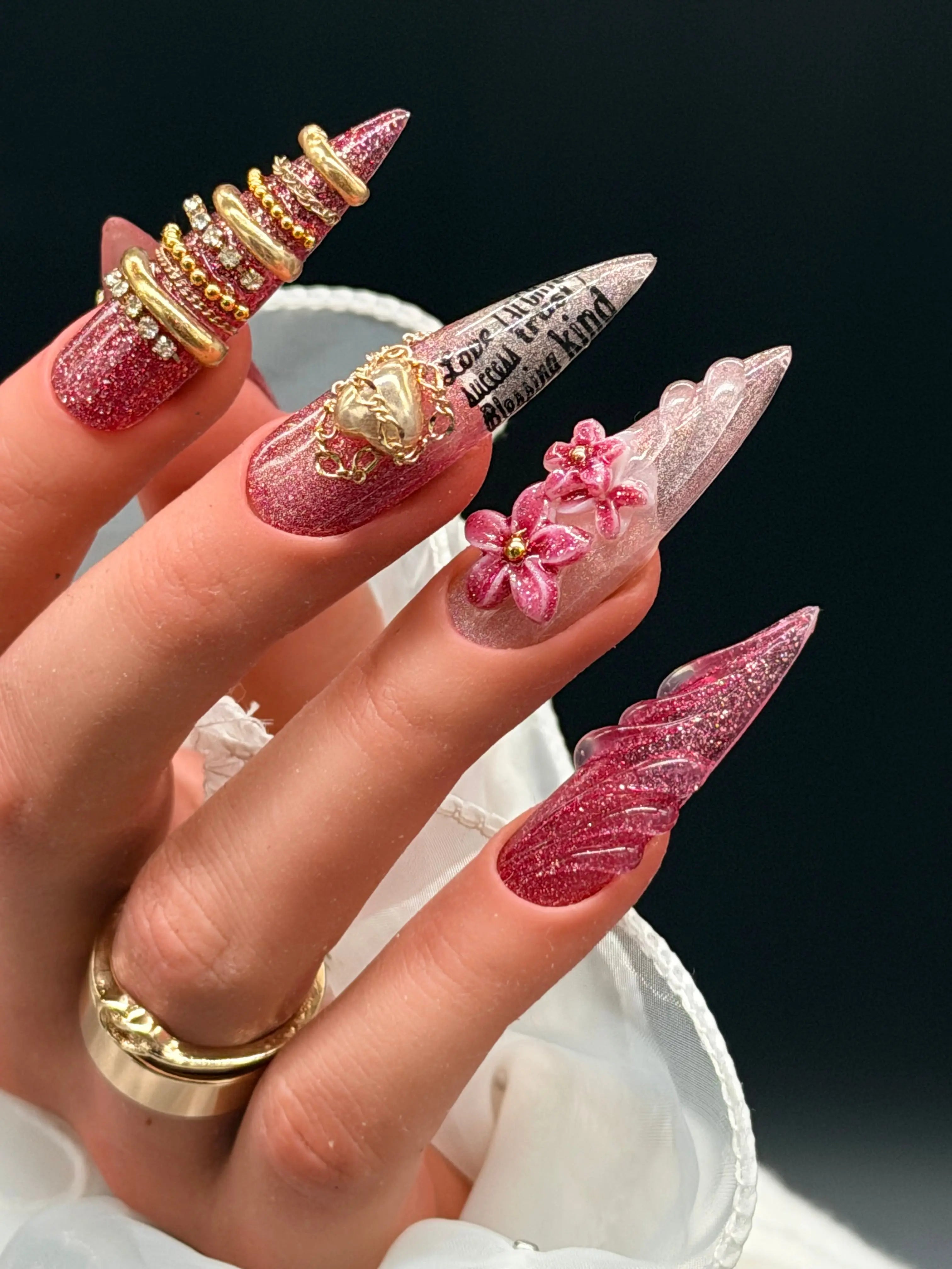 Burgundy stiletto press-on nails with gold sculpted accents, 3D floral details, and glitter shimmer finish