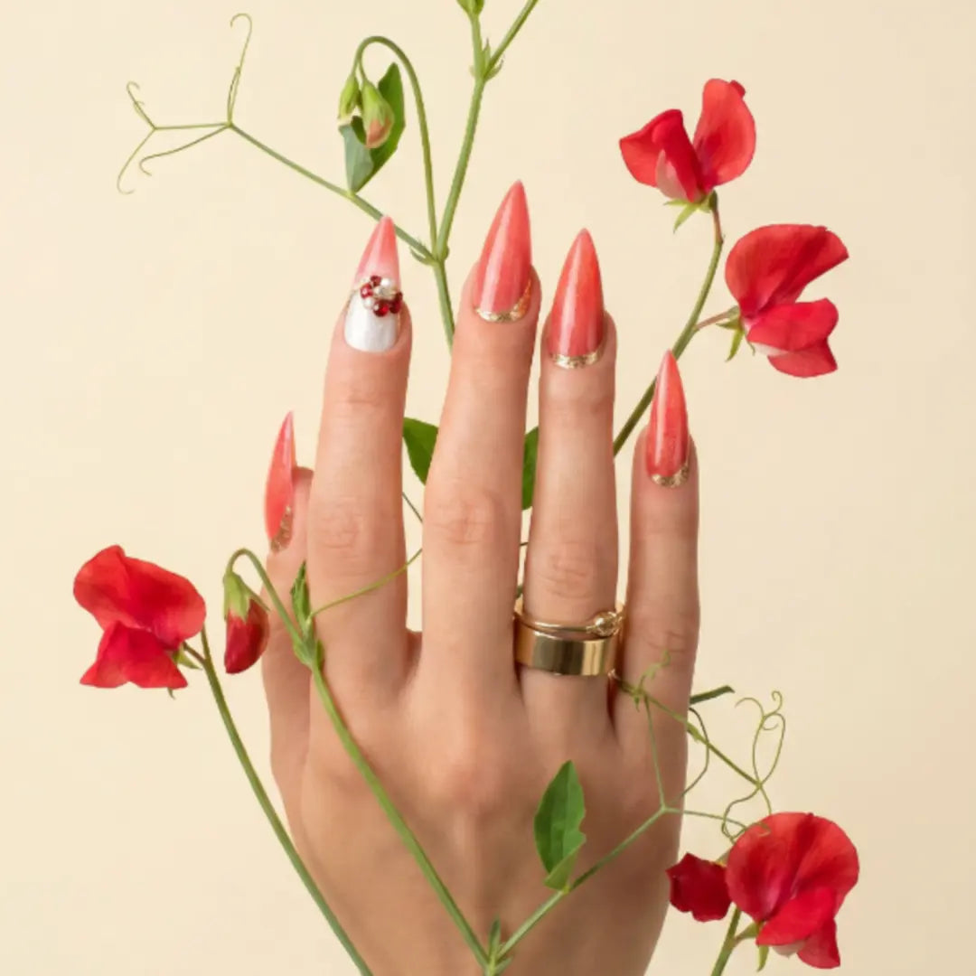 
Luxury stiletto press-on nails in vibrant coral red with gold detailing and a crystal accent nail, handcrafted with a glossy gel finish from the At Sunset Collection.
