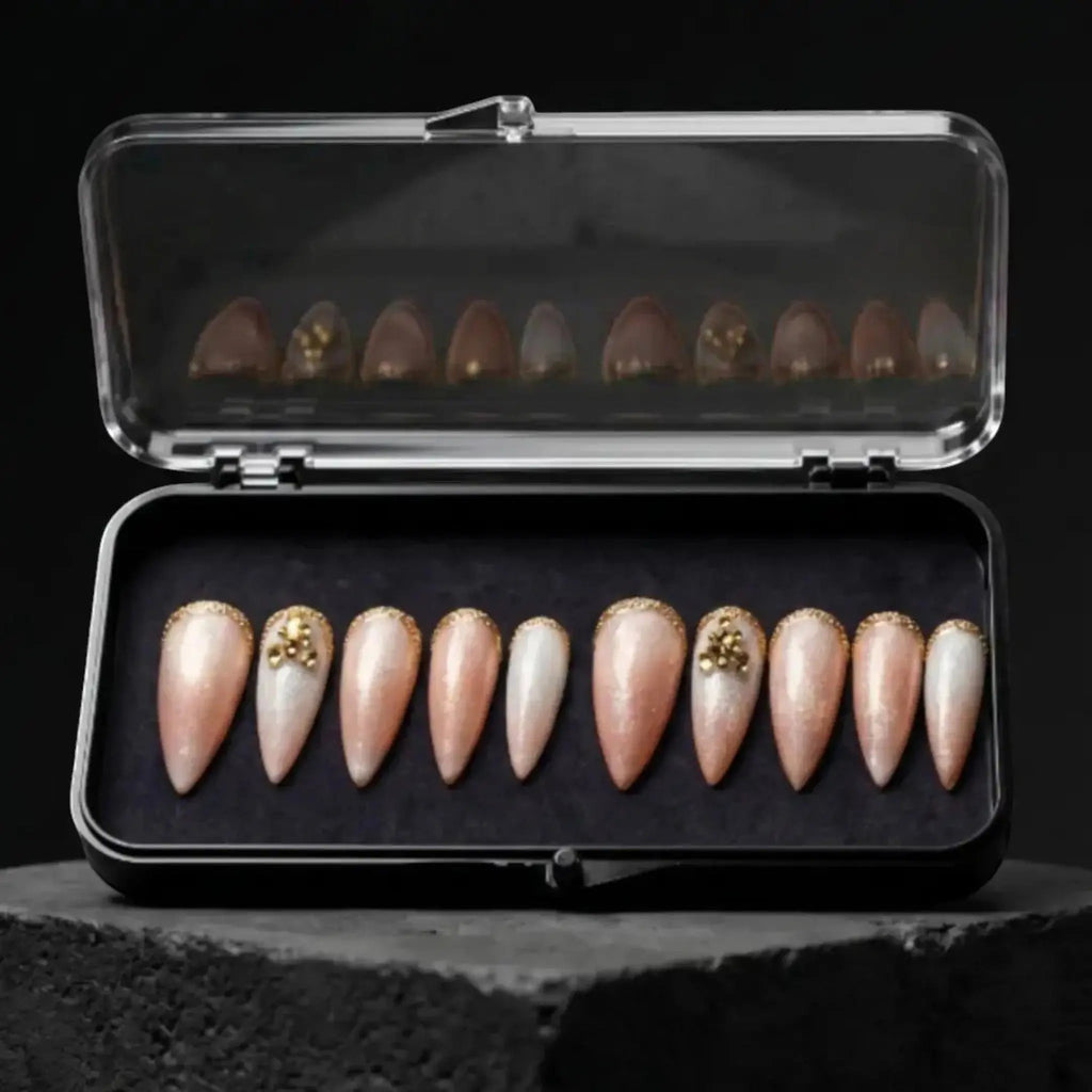 Press to Impress Antigua luxury press-on nails with champagne shimmer, ivory accents, and gold glitter embellishments.