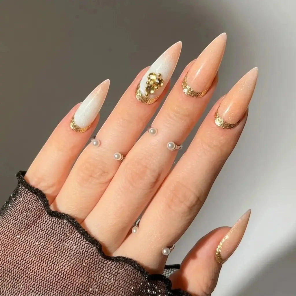 Press to Impress Antigua luxury stiletto press-on nails with champagne shimmer, ivory accents, and gold glitter details.