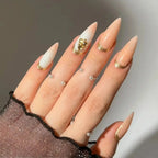 Press to Impress Antigua luxury stiletto press-on nails with champagne shimmer, ivory accents, and gold glitter details.