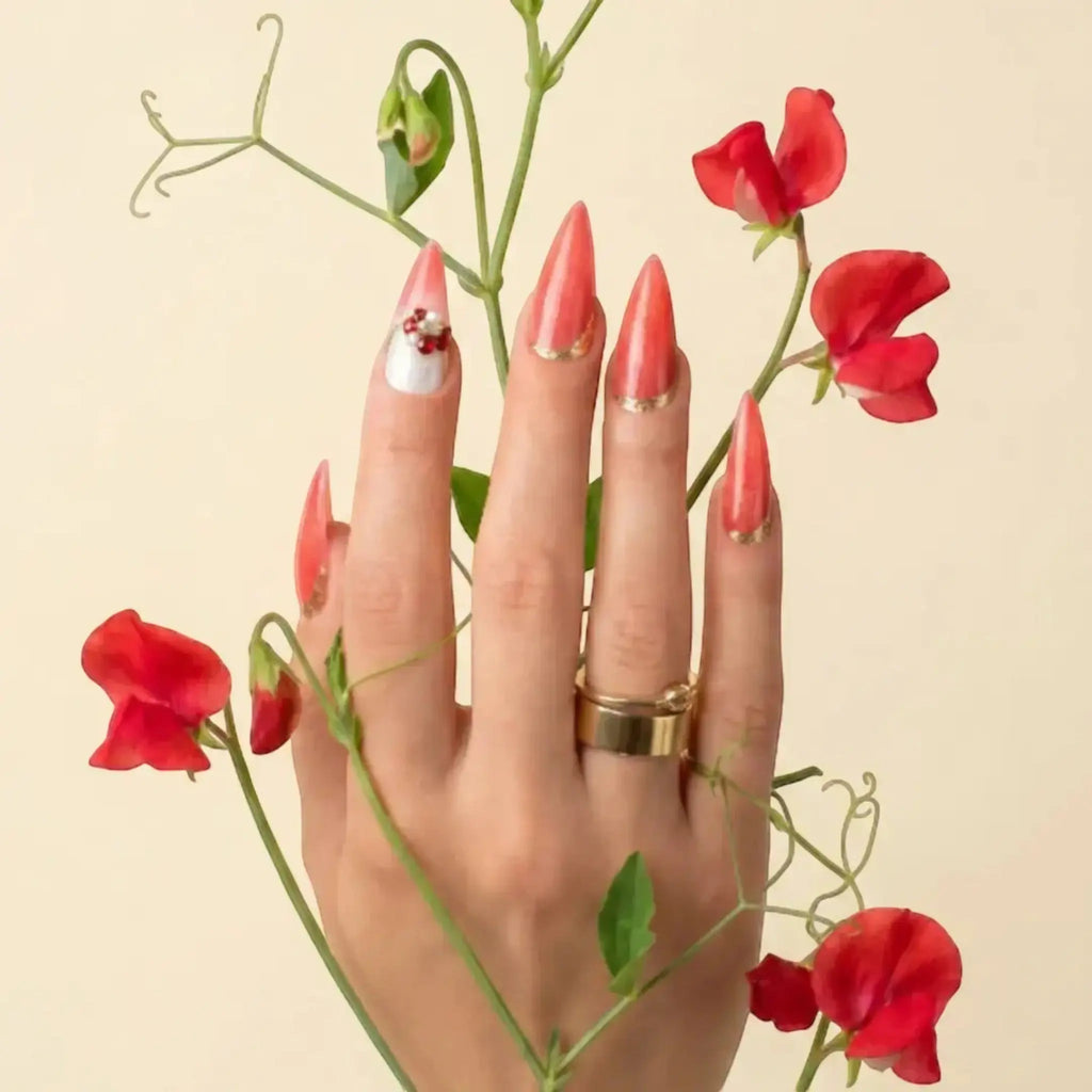 Press to Impress Saint Lucia coral-red stiletto press-on nails with gold accents and crystal embellishments.