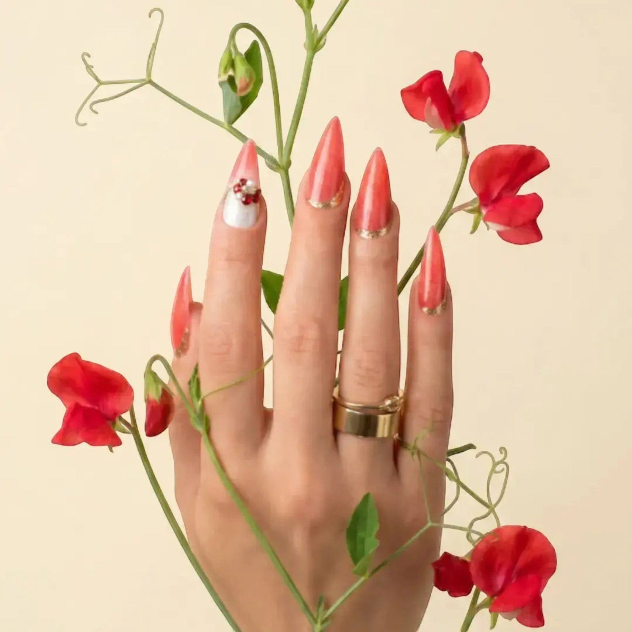Press to Impress Saint Lucia coral-red stiletto press-on nails with gold accents and crystal embellishments.