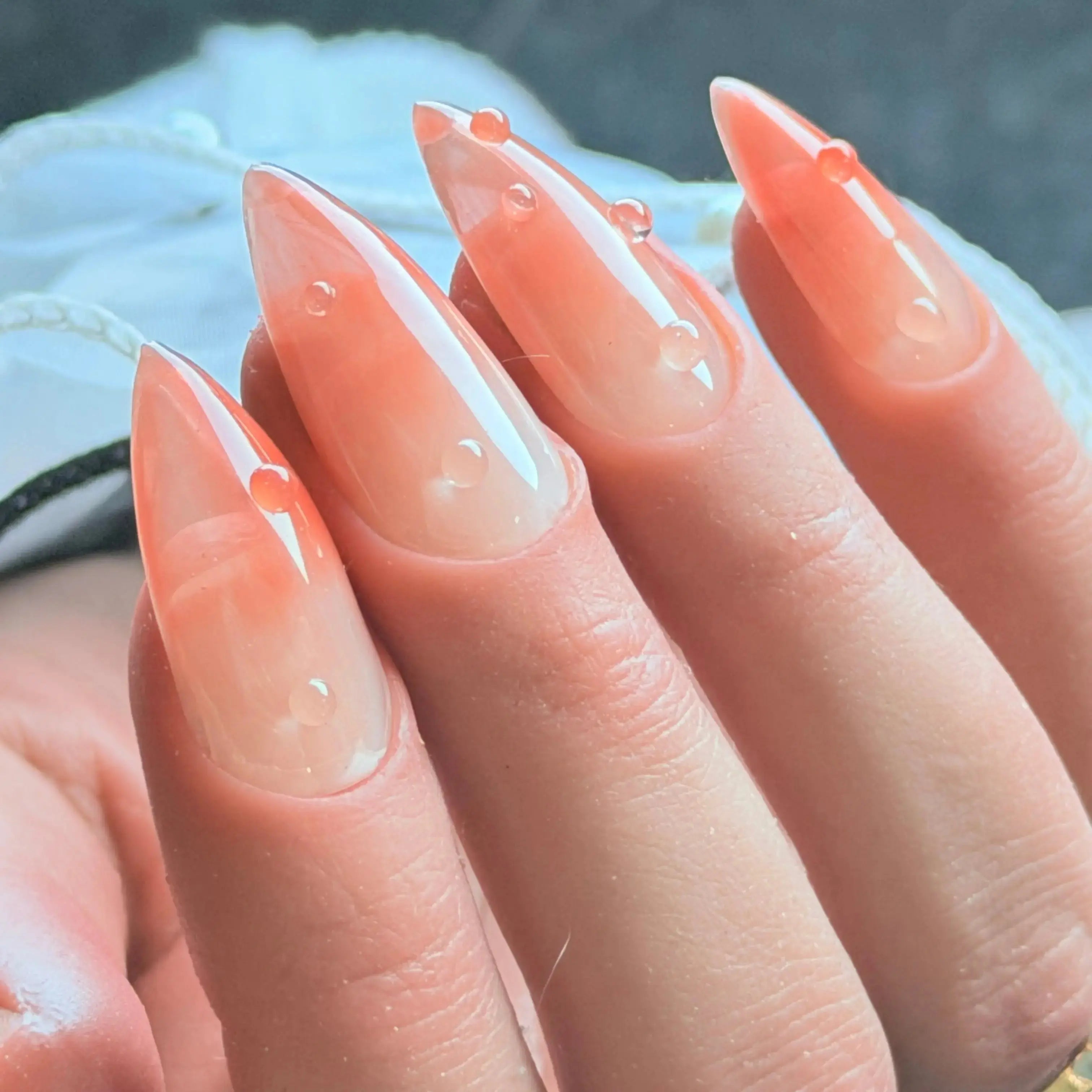 Press to Impress Dew Kiss peachy nude stiletto nails with glossy water droplet accents and a dewy finish.