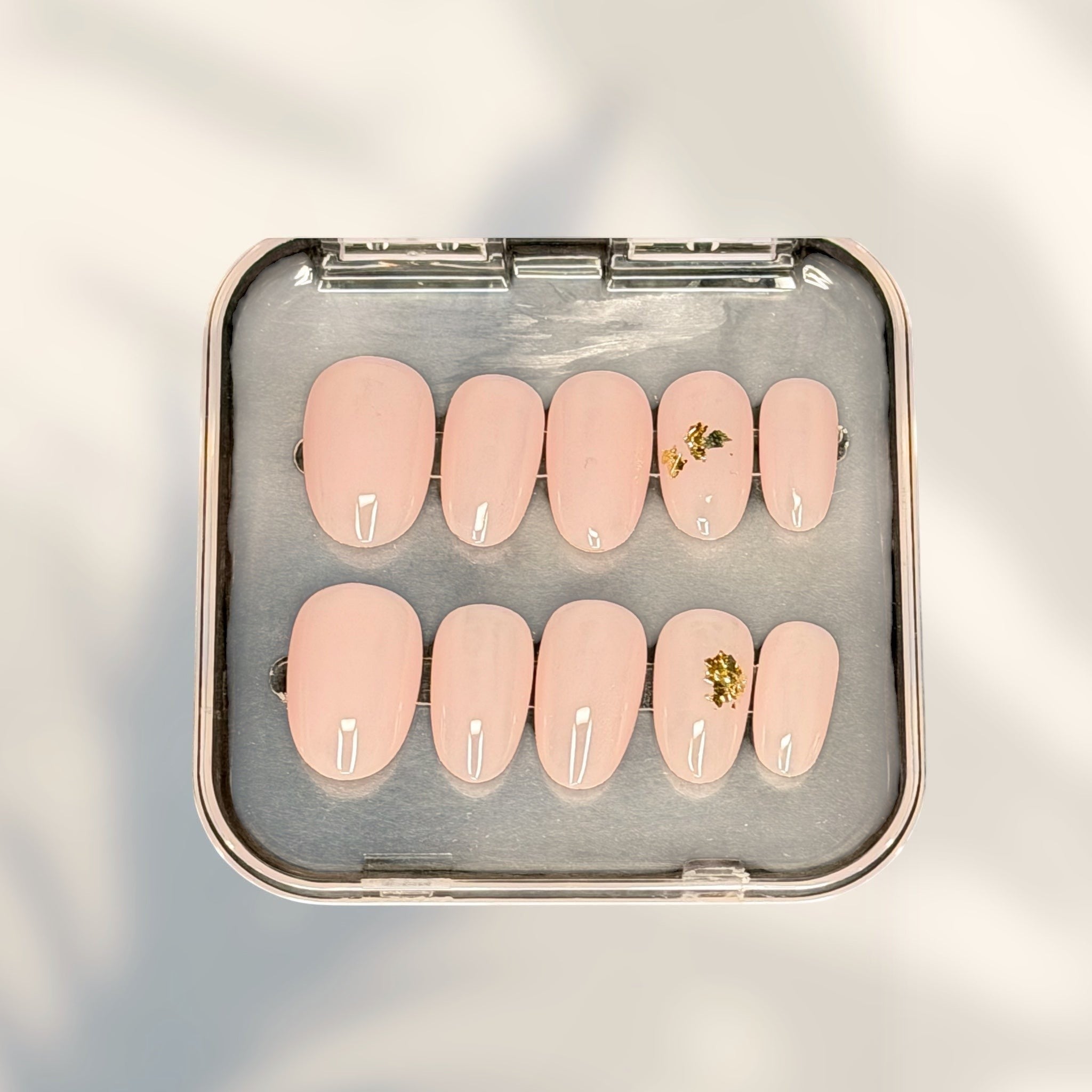 Press to Impress Gilded Whisper short round press on nails in soft pink nude with gold flakes.