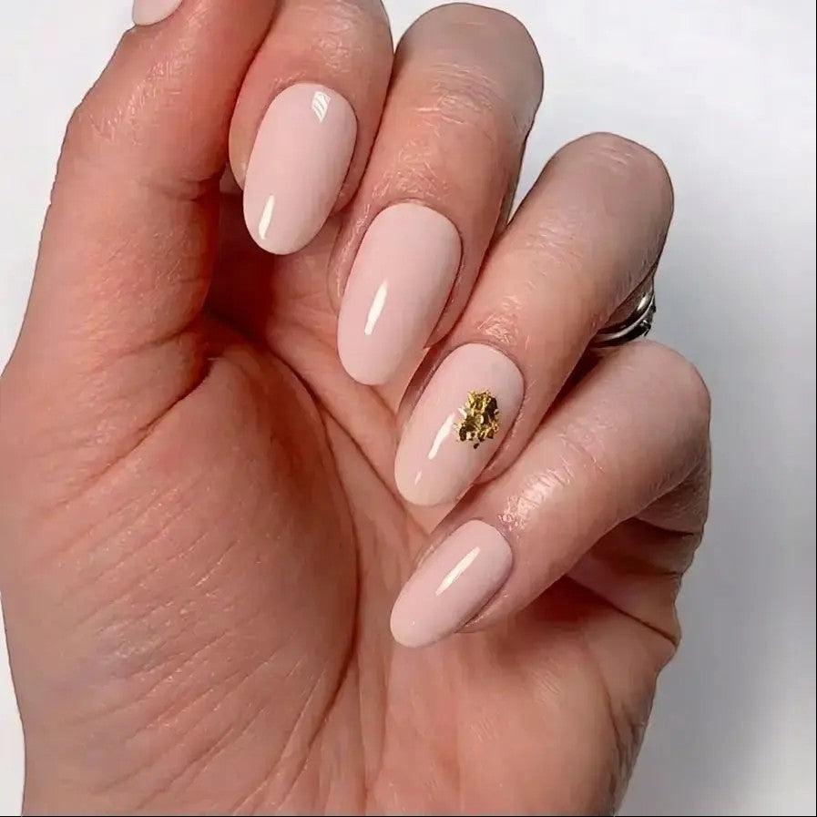 Press to Impress Gilded Whisper short round press-on nails in soft pink nude with gold flakes.