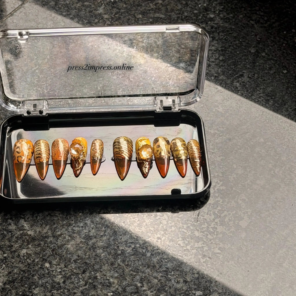 Press to Impress Golden Safari press-on nails with amber glass French tips, animal print, and gold gem accents.