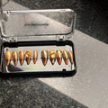 Press to Impress Golden Safari press-on nails with amber glass French tips, animal print, and gold gem accents.