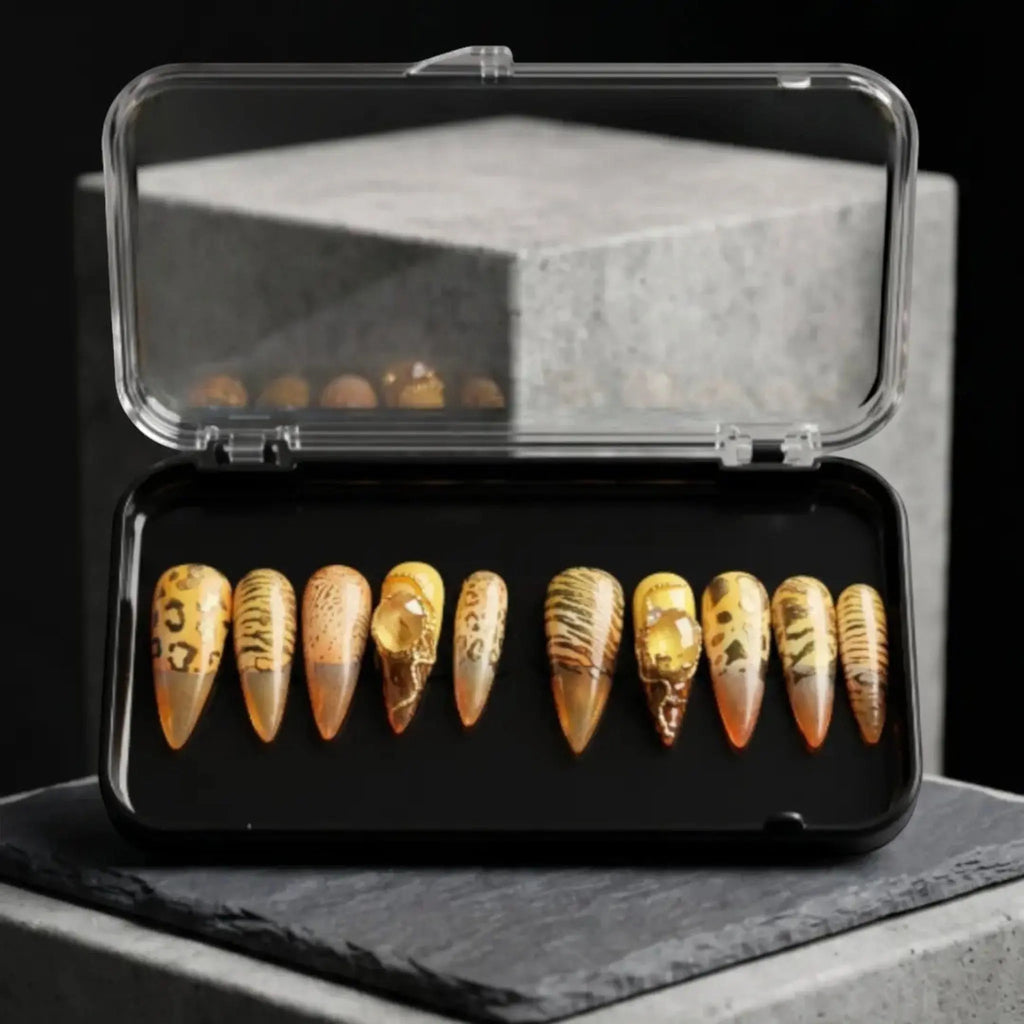 Press to Impress Golden Safari press-on nails with amber glass French tips, animal print, and gold accents in a case.