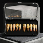 Press to Impress Golden Safari press-on nails with amber glass French tips, animal print, and gold accents in a case.