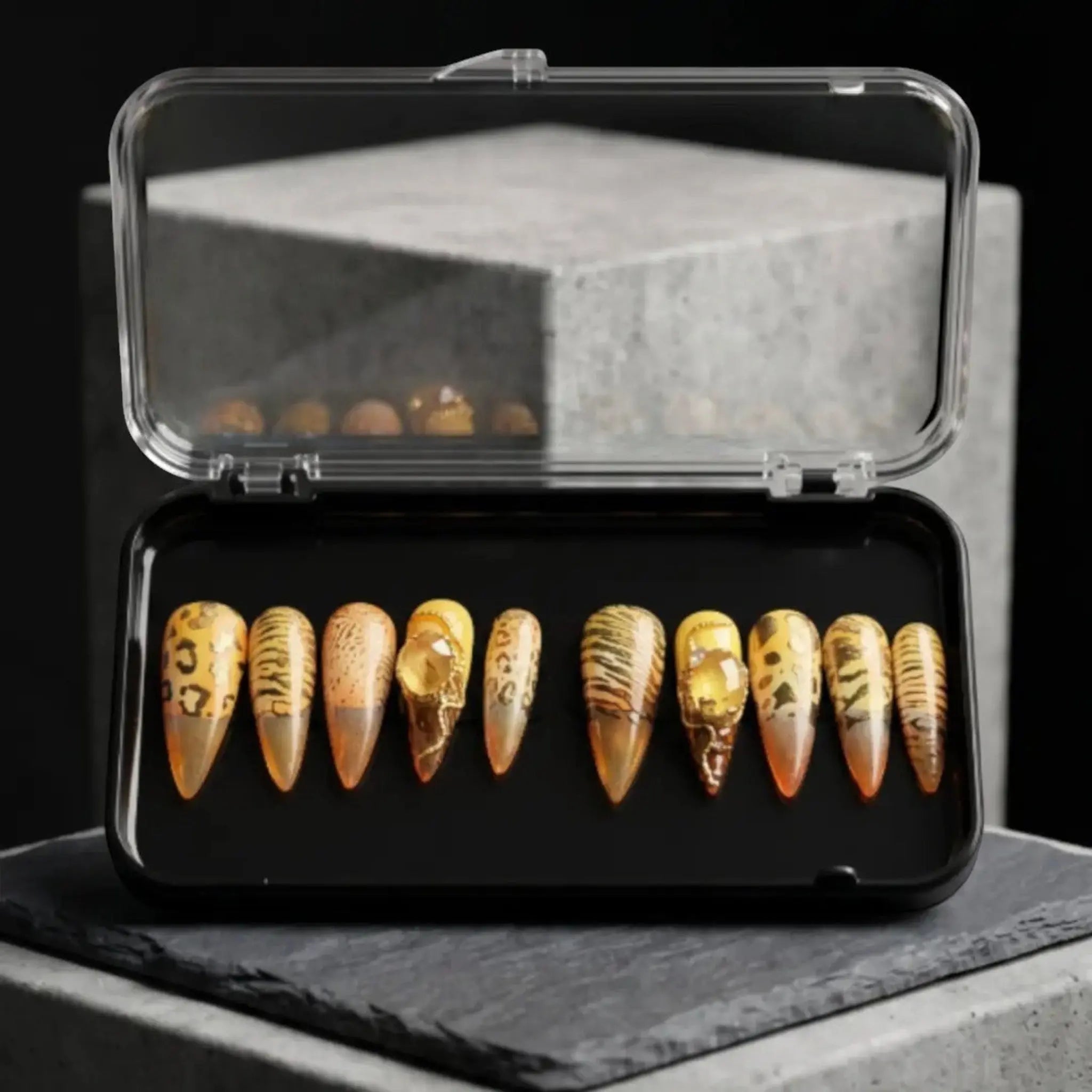 Press to Impress Golden Safari press-on nails with amber glass French tips, animal print, and gold accents in a case.