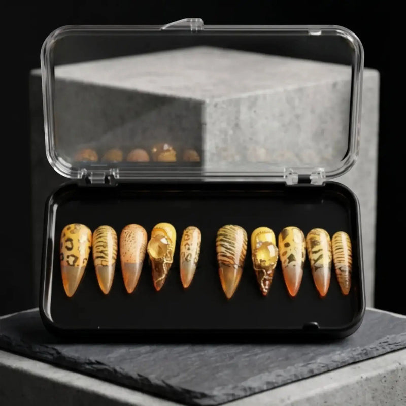 Press to Impress Golden Safari press-on nails with amber glass French tips, animal print, and gold accents in a case.