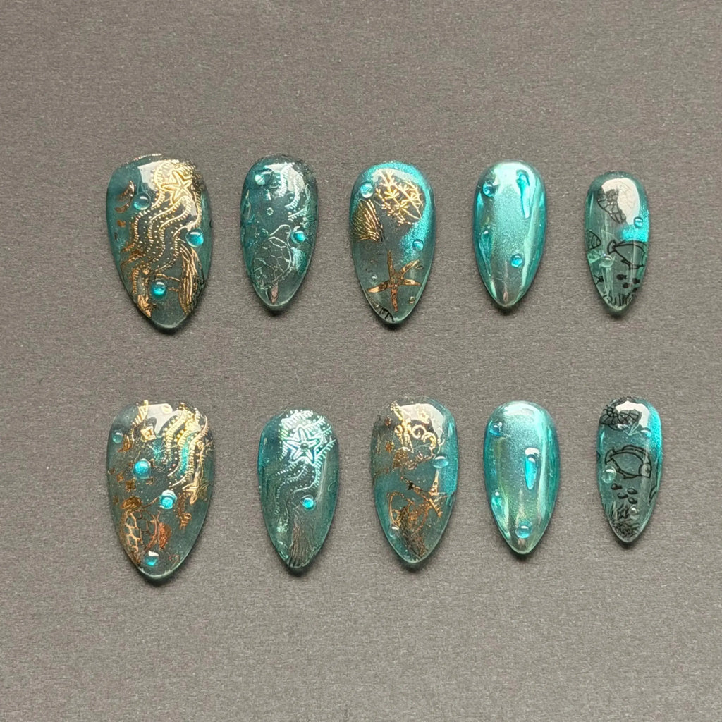 Press to Impress Lost Atlantis luxury press-on nails in seafoam chrome with gold ocean details and blue gems.