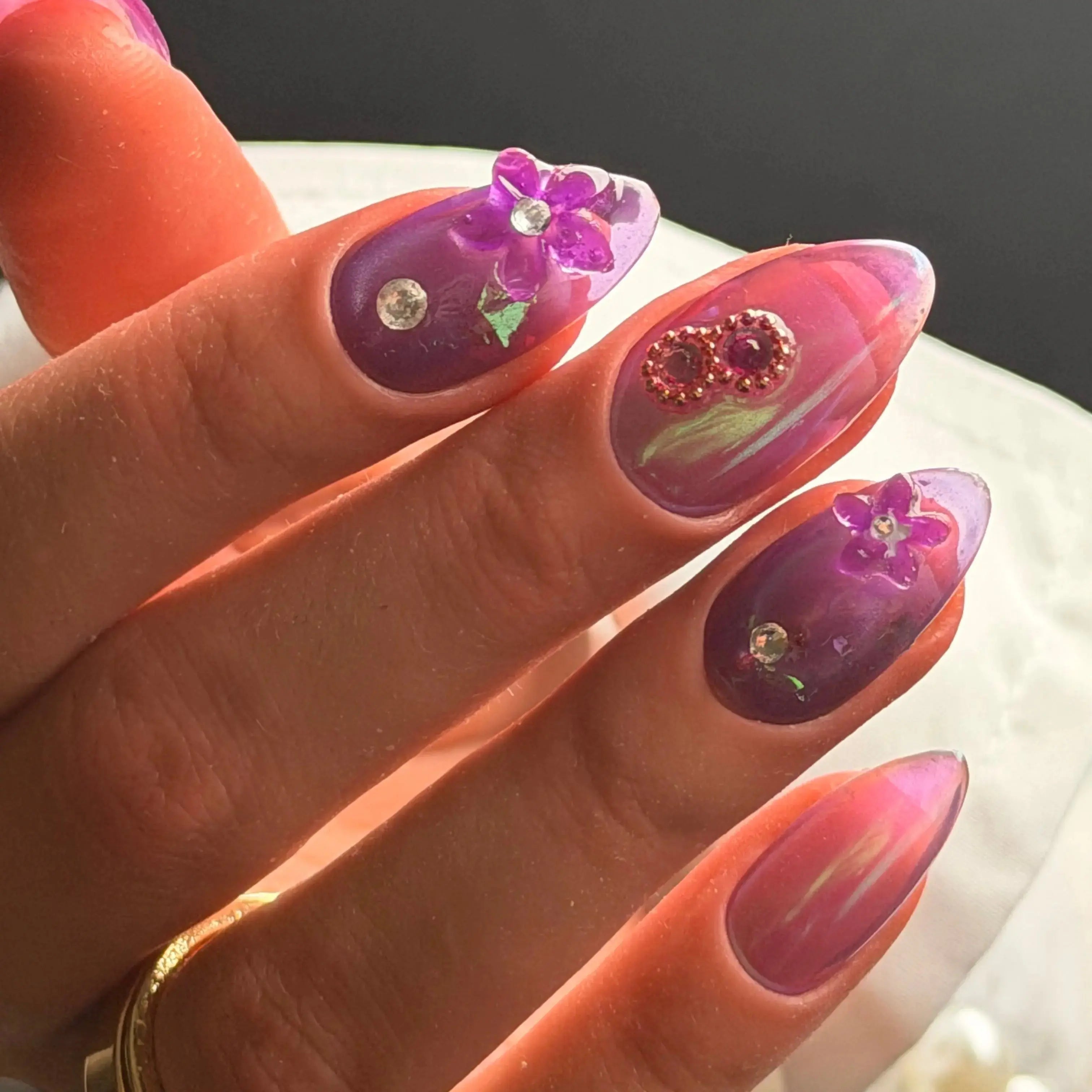 Press to Impress Orchid Mirage iridescent chrome nails with sculpted floral accents and crystal embellishments in violet hues.