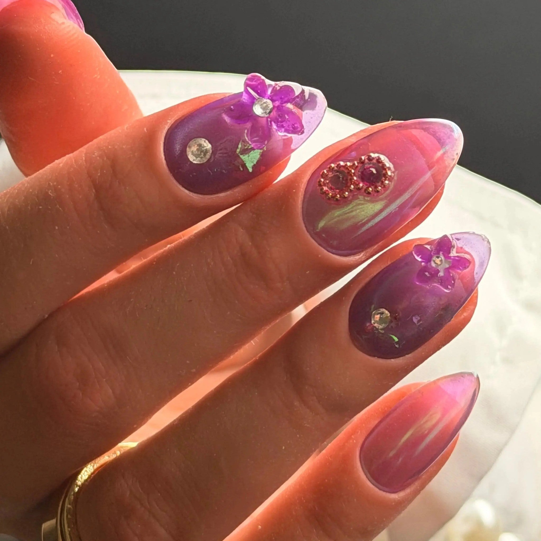 Press to Impress Orchid Mirage iridescent chrome nails with sculpted floral accents and crystal embellishments in violet hues.
