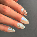 Press to Impress Pearl Cove iridescent almond nails with shell and starfish accents. Pearlescent finish.