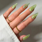 Press to Impress Pistachio Veil stiletto nails with luminous shimmer and translucent detailing, featuring gold rings.