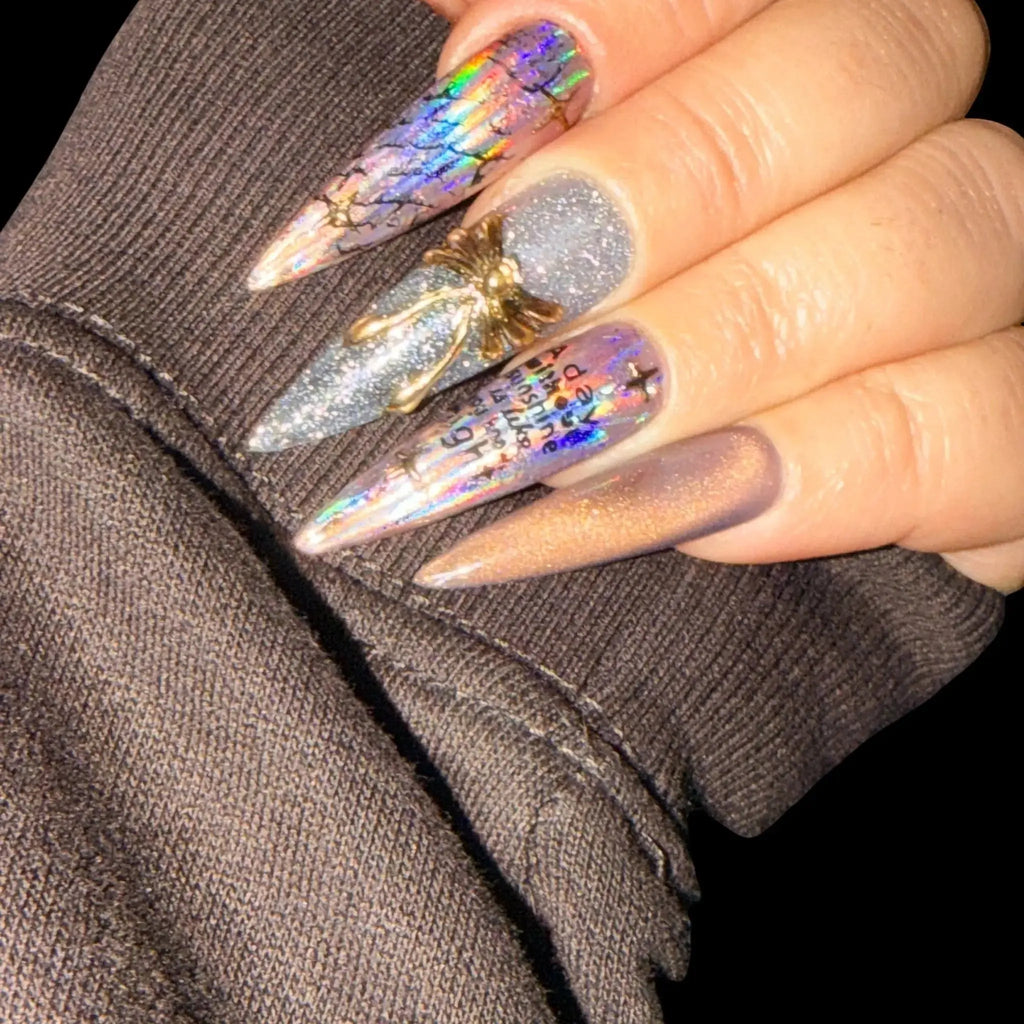 Press to Impress Prism Eclipse stiletto press-on nails with holographic foil, silver glitter, chrome accents, and gold embellishment.