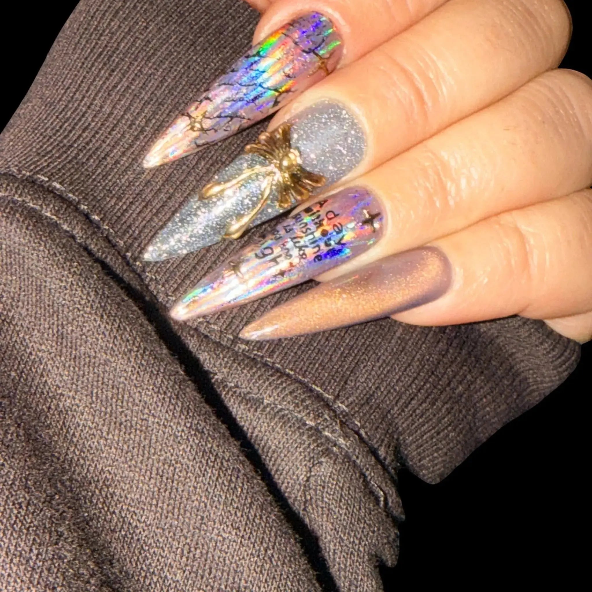 Press to Impress Prism Eclipse stiletto press-on nails with holographic foil, silver glitter, chrome accents, and gold embellishment.