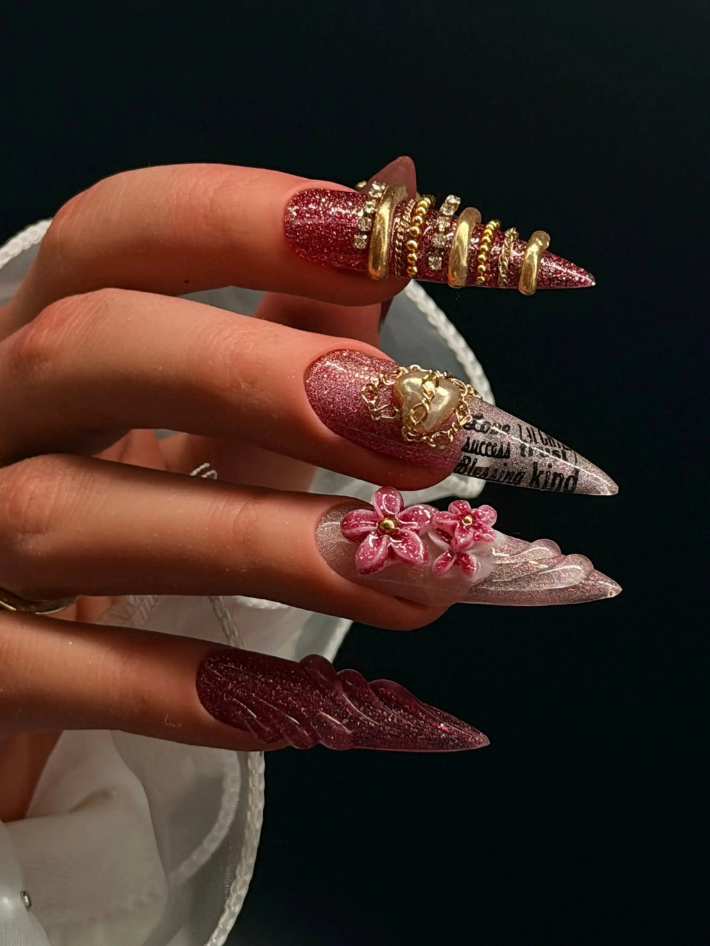 Press to Impress Rouge Sculpt stiletto press-on nails with red-pink glitter, 3D flowers, gold chains, and heart charm.