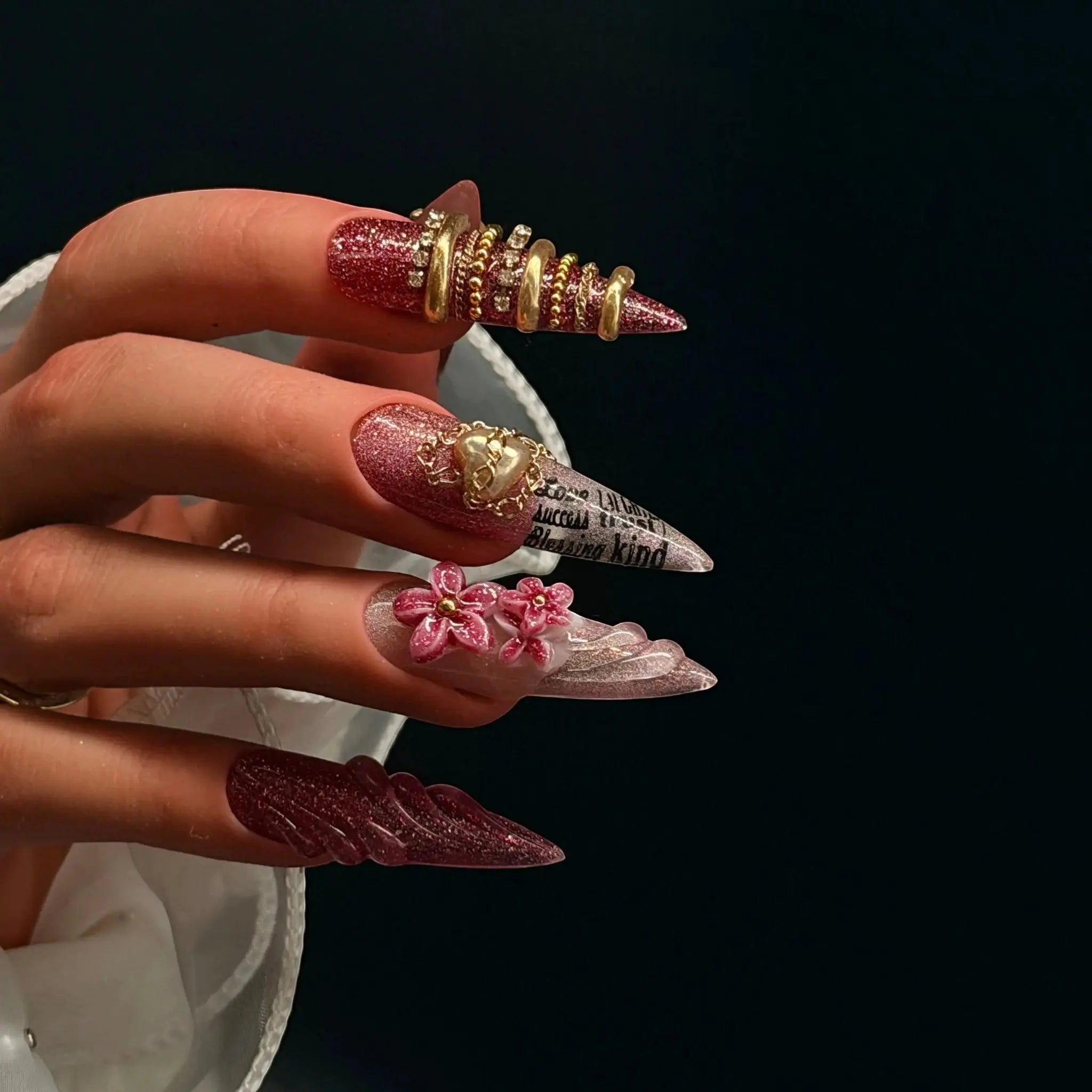 Press to Impress Rouge Sculpt stiletto press-on nails with red-pink glitter, 3D flowers, gold chains, and heart charm.