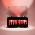 Press to Impress Saint Lucia press-on nails in coral-red with gold tips, white accents, and crystal embellishments.