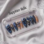 Press to Impress Saphire Relic stiletto press-on nails in blue, nude, with cross designs and rhinestones.