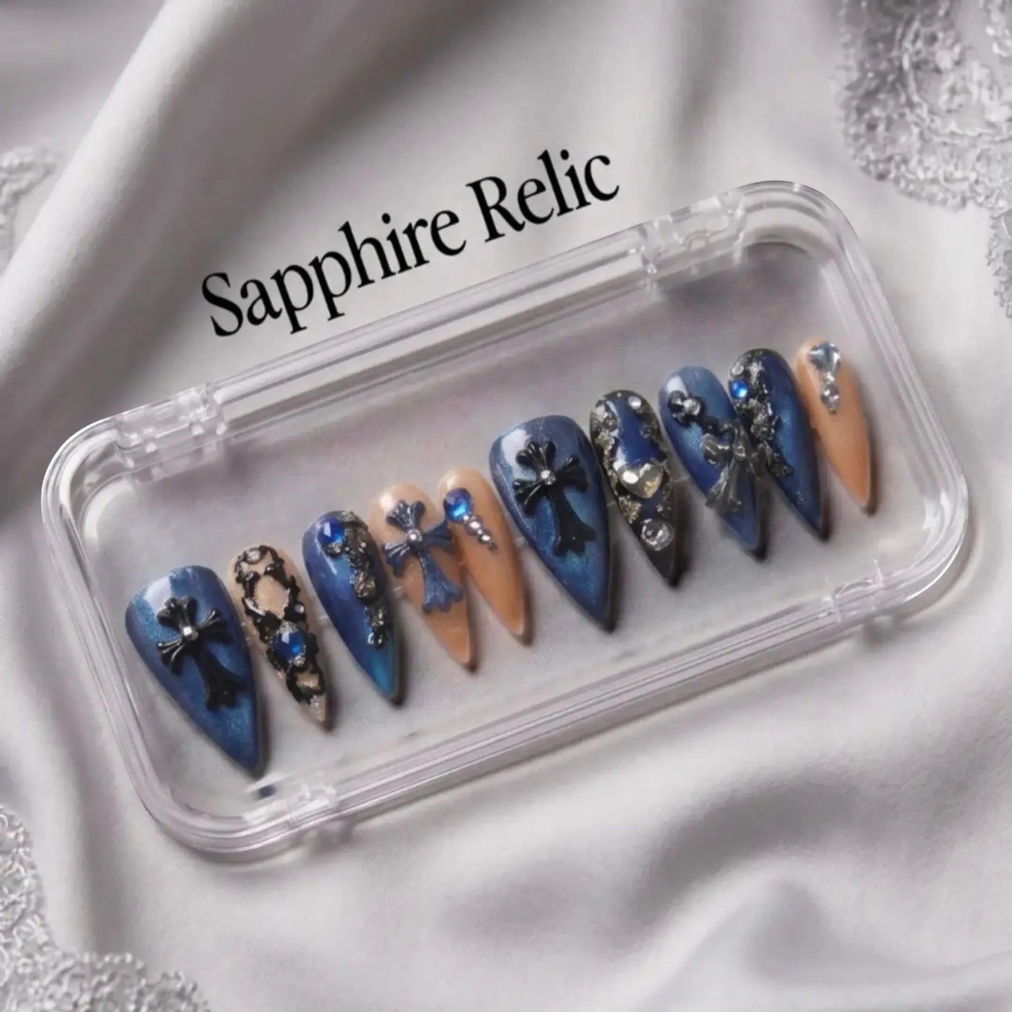 Press to Impress Saphire Relic stiletto press-on nails in blue, nude, with cross designs and rhinestones.