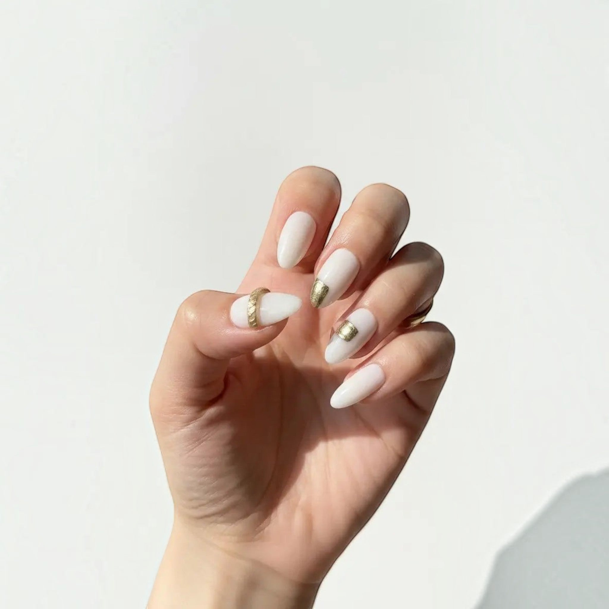 Press to Impress Gold Muse almond-shaped press-on nails with milky white base and gold accents.