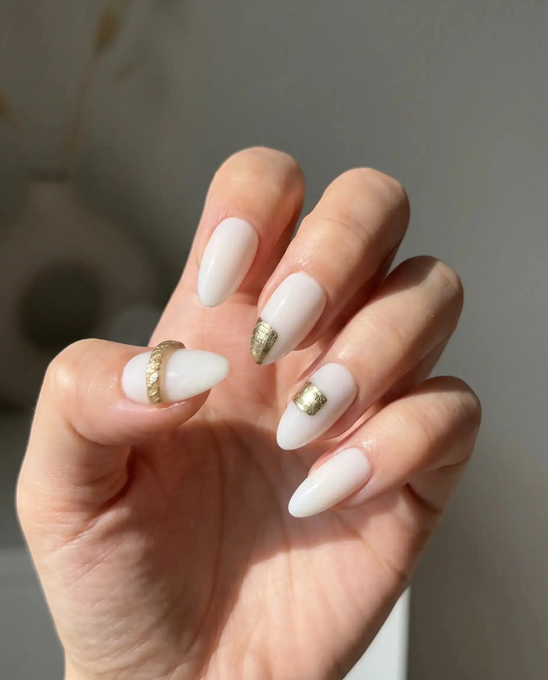 Press to Impress Gold Muse almond-shaped nails with milky white base and gold foil accents. Elegant design for everyday or special occasions.