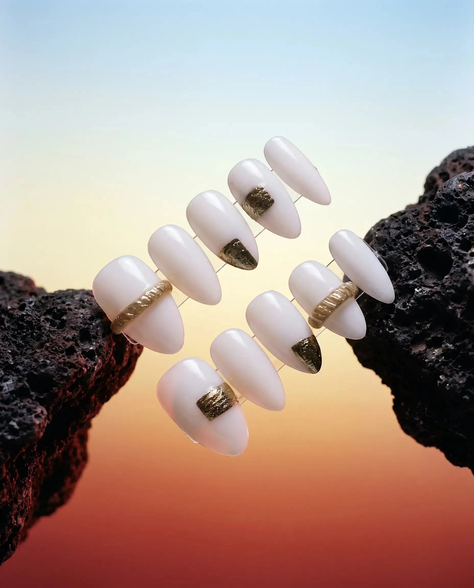 Press to Impress Gold Muse almond-shaped press-on nails in milky white with gold accents and textured gold details.
