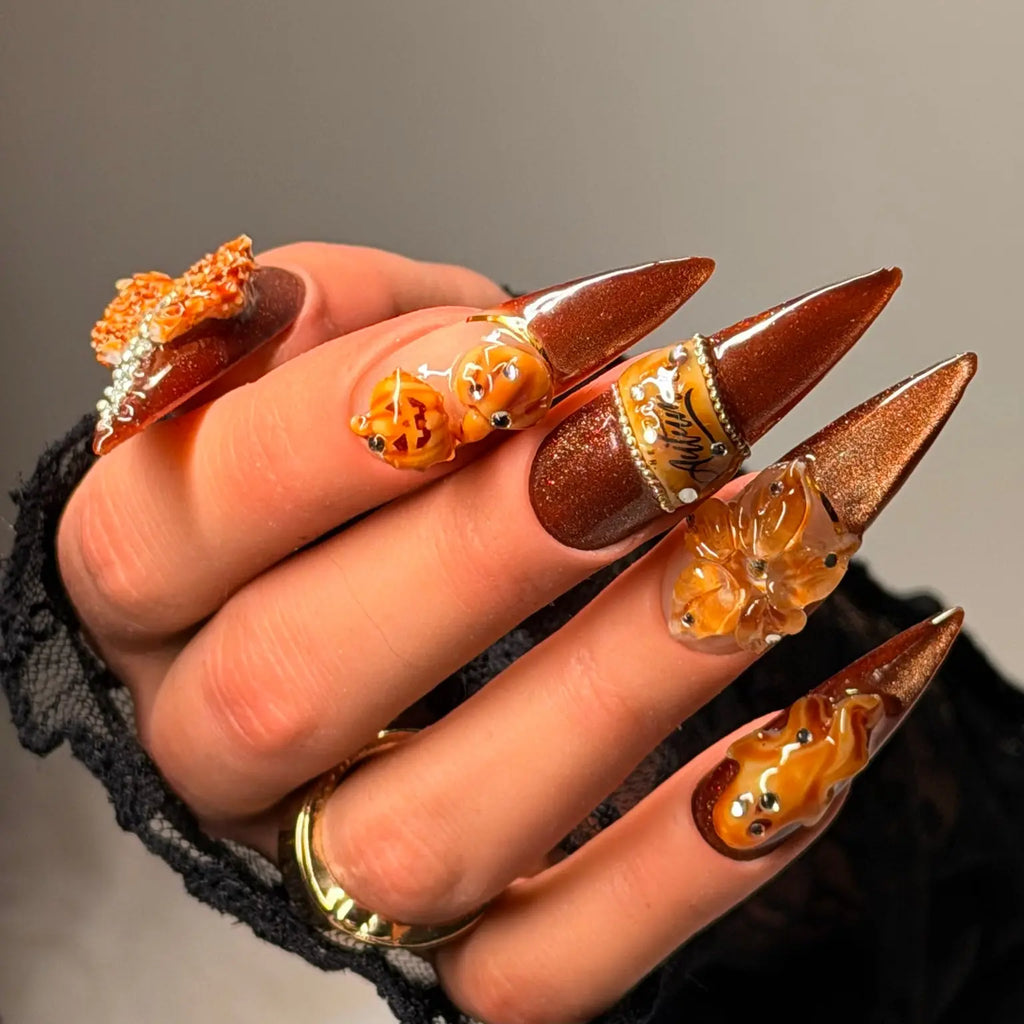 Angled view of Pumpkin Hour copper shimmer stiletto nails with pumpkin and amber sculptural details