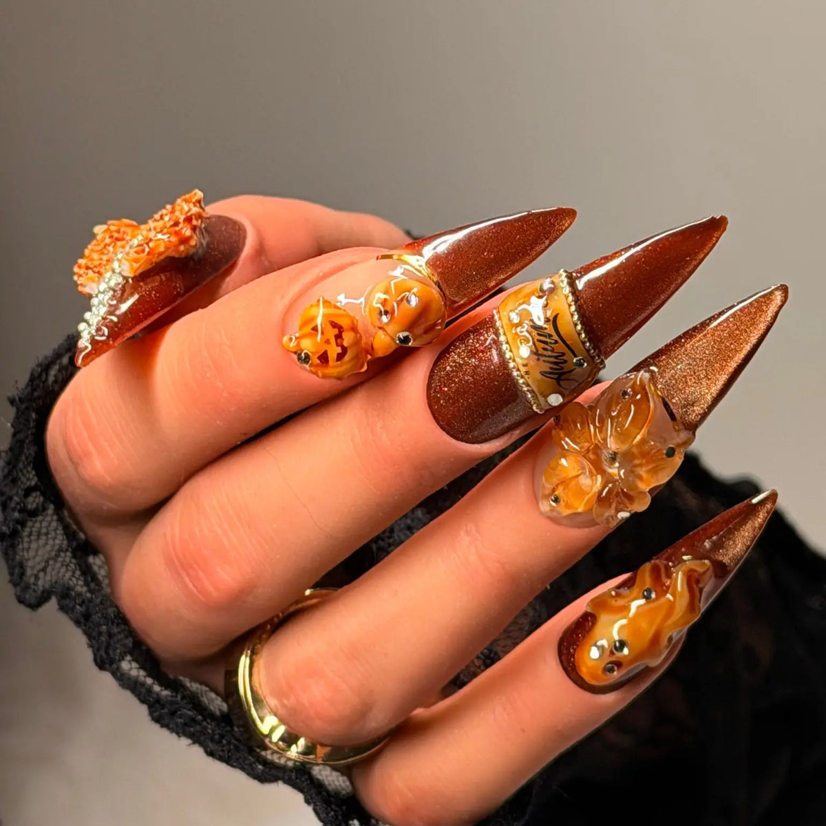 Angled view of Pumpkin Hour copper shimmer stiletto nails with pumpkin and amber sculptural details