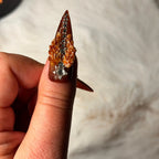 Close-up of 3D pumpkin and amber floral accents on long copper Halloween nails